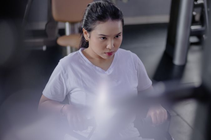 Determined woman strengthens back on rowing machine at the gym