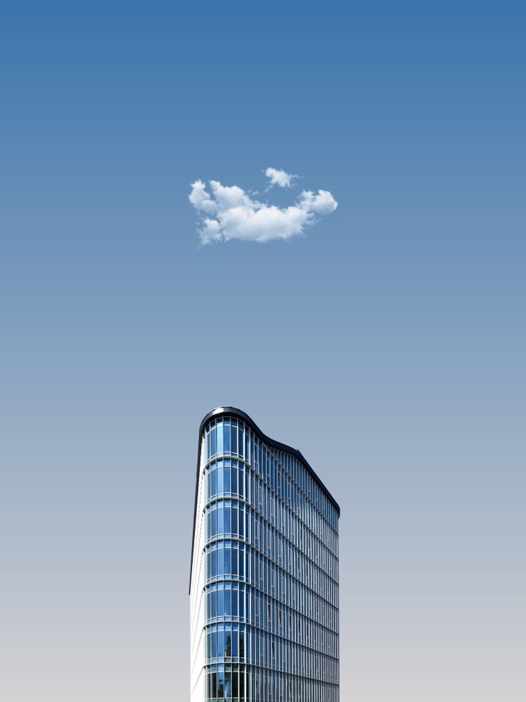 Top part of glass skyscraper building with small cloud above