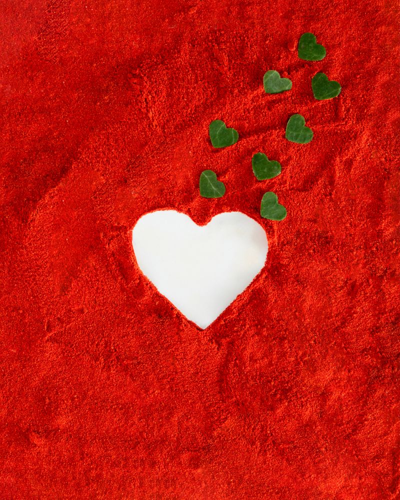 Heart shape surrounded by red soil with green leaves