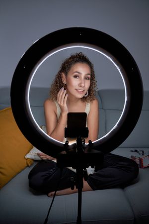 Smiling blogger woman demonstrating makeup shooting video on sma