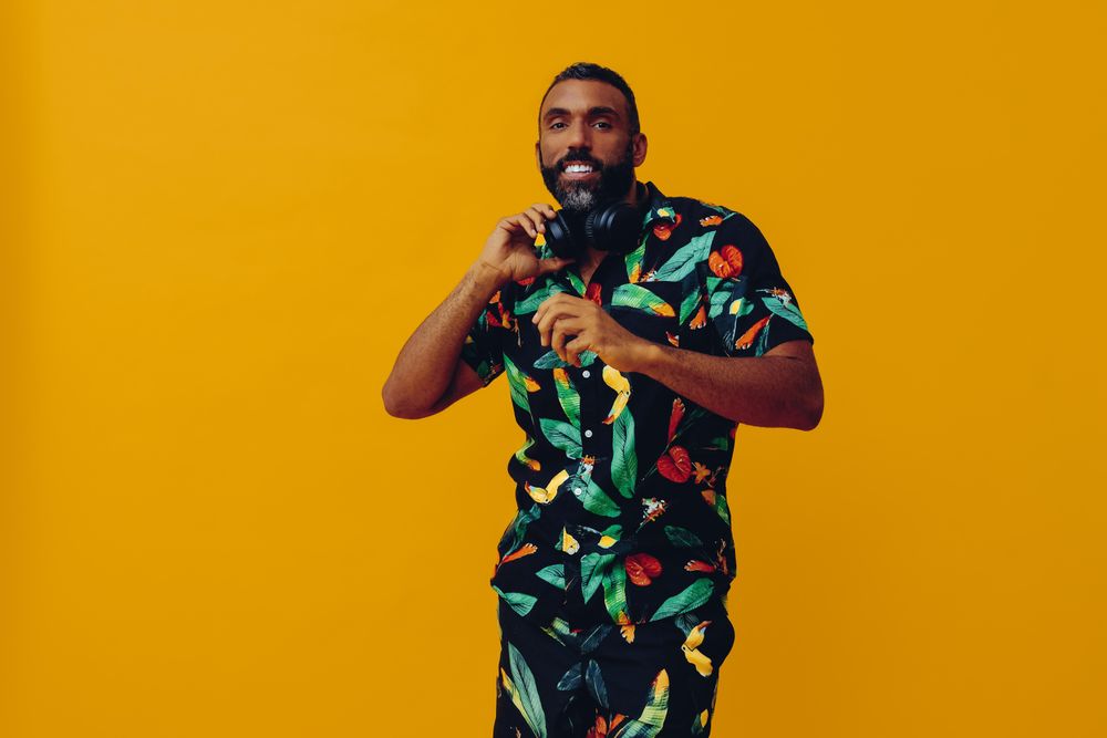 Black male in bold patterned shirt wearing headphones in yellow room