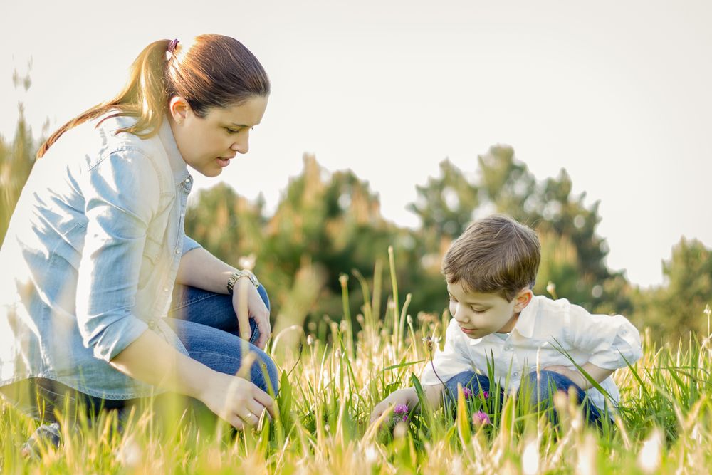Pregnant mother and son picking flowers in a field