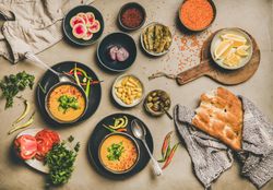 Spread of yellow lentil soup bowls, with bread, and vegetable garnishes