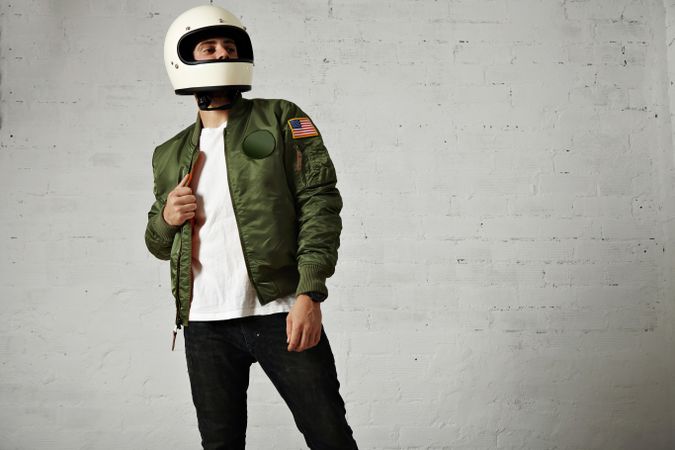 Man opening green jacket wearing biker helmet in studio shoot