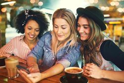 Three female friends looking at something on a cellphone