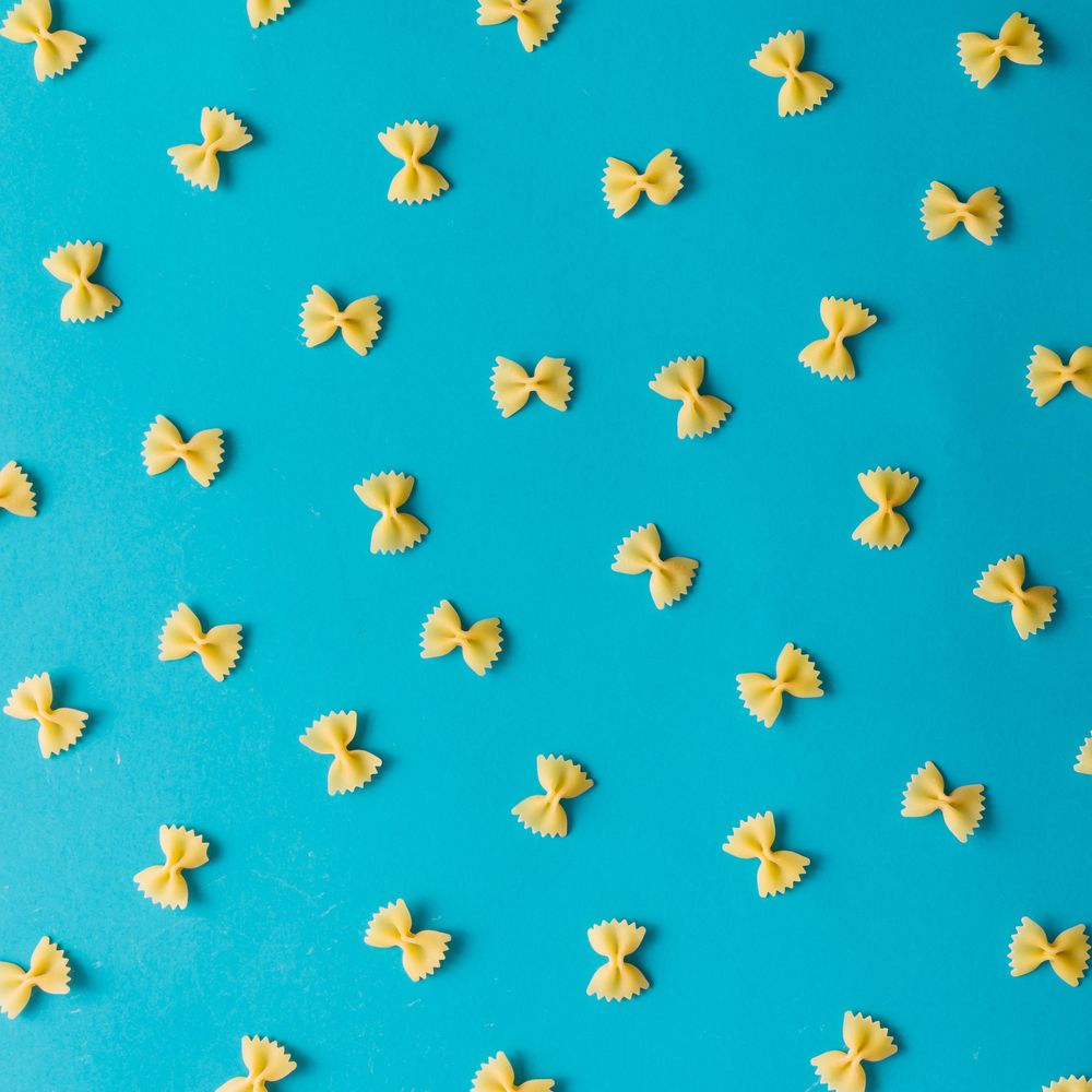 Pattern made of bow-tie pasta on blue background