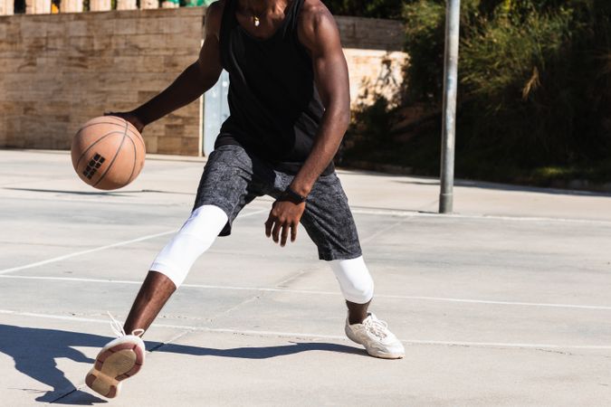 Anonymous Black man playing basketball on sports ground