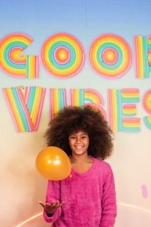 Cheerful Black girl with air balloons in studio