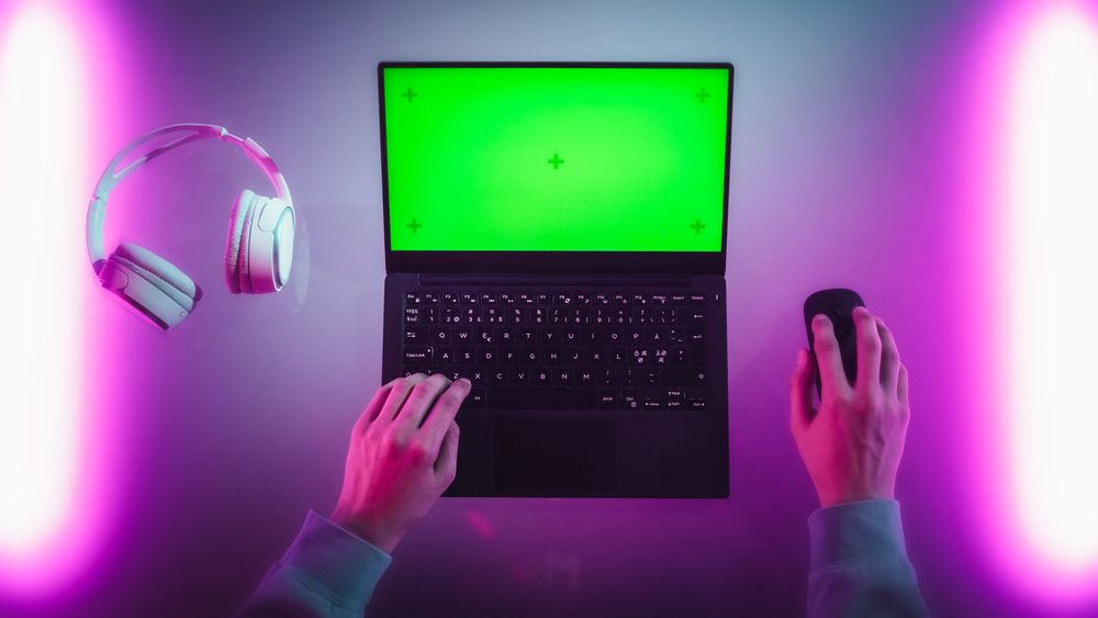 Anonymous Designer Typing on a Laptop with Mock-Up Green Screen Chromakey Display. Software Developer or Gamer Using a Computer, Working on a Creative Project, Chatting with Team. Top Down View