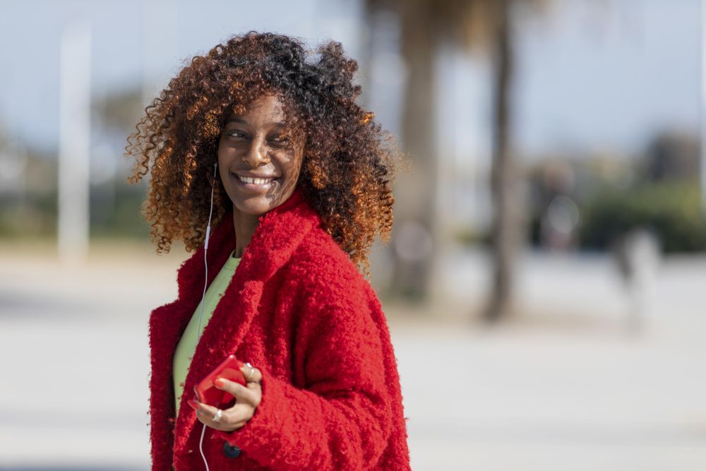 Smiling female in red jacket on street with palm trees