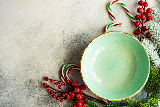 Top view of green wintry plate with candy cane and holly with copy space