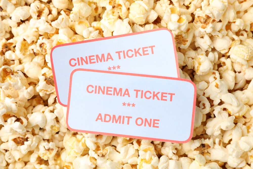 Cinema tickets on popcorn background, close up