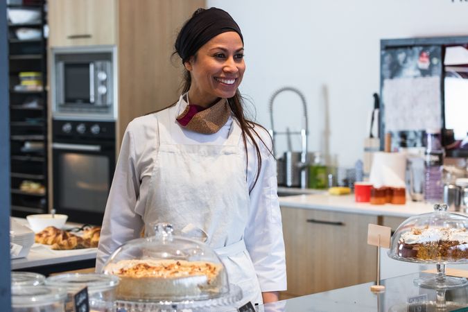 Cheerful baker standing at counter in bakery