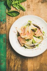 Top view of ham and pear in bowl, on green trimmed wooden background