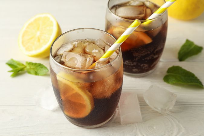 Glasses with cold cola and citrus on cement background, closeup
