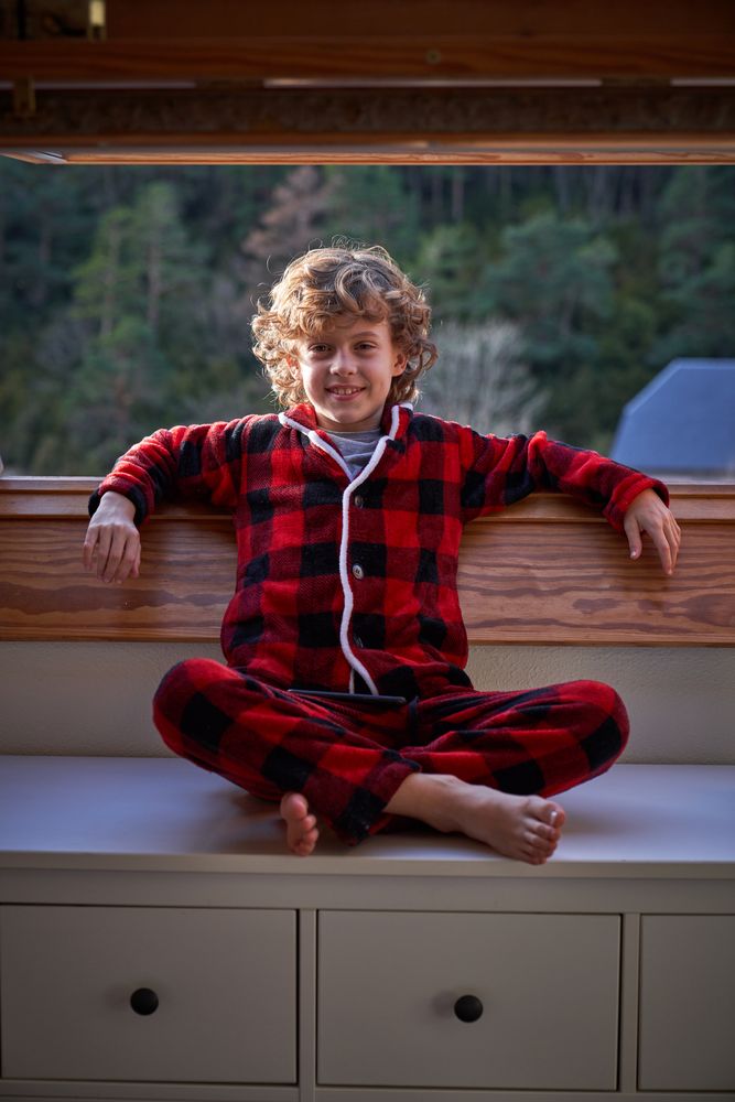 Positive boy sitting on cabinet near window in apartment