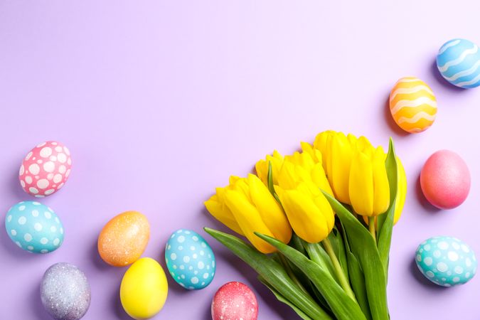 Flat lay composition with Easter eggs and flowers on color background, space for text. Top view