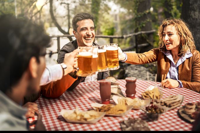 Group of cheerful friends toasting beer glasses