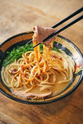 Ramen with tender pork slice between chopsticks
