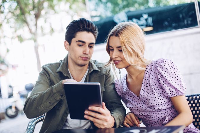 Happy young couple using tablet outdoors