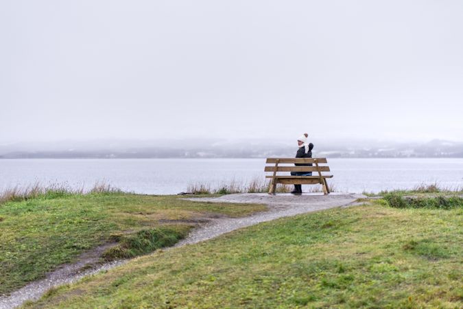 Woman sitting on bench on rainy day