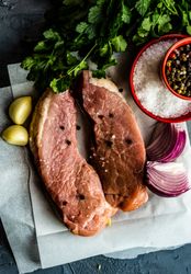 Top view of two raw pork chops with onion, garlic and herbs