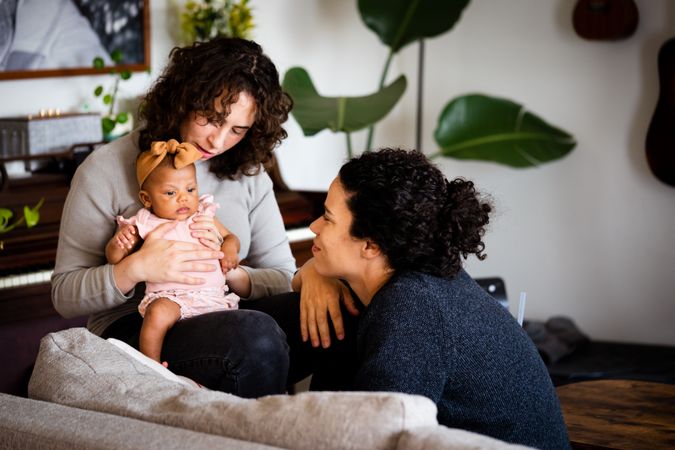 Two new moms sitting with baby in living room