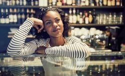 Contemplative woman leaning on glass display in modern bistro