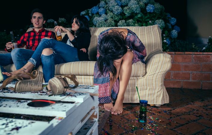 Inebriated woman sitting on the sofa on a party with her head in her lap