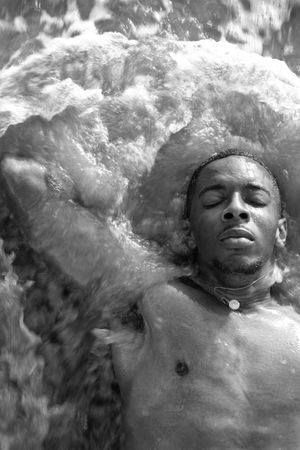 Grayscale portrait of topless man laying in water