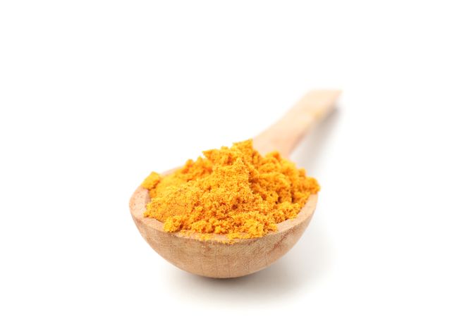 Close up top view of wooden spoon with a yellow powdered spice