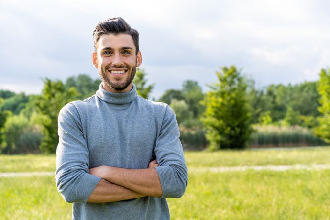 Confident smiling man standing in a park