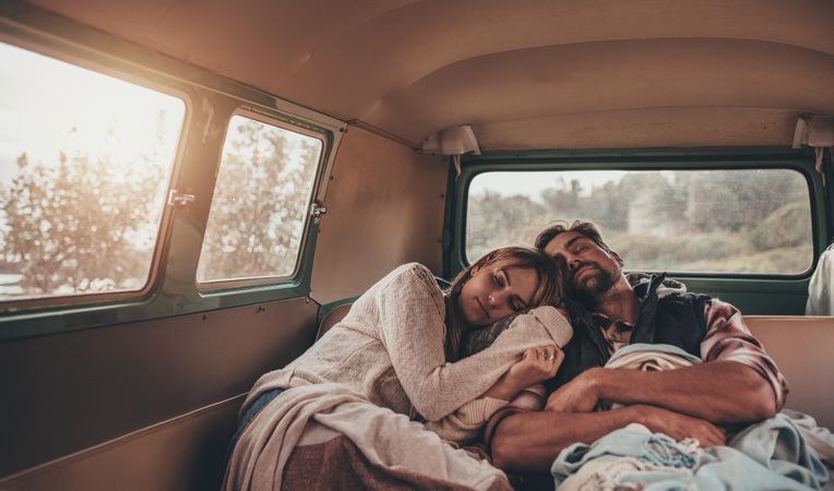 Friends sleeping together in van on road trip