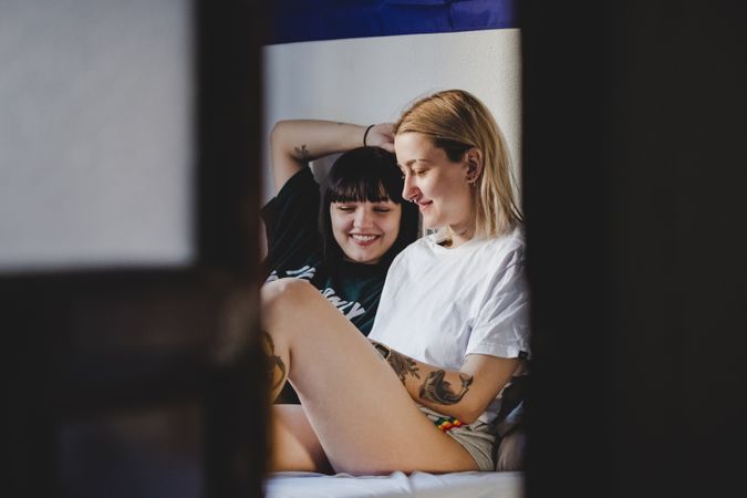 Happy lesbian couple using smartphone on bed