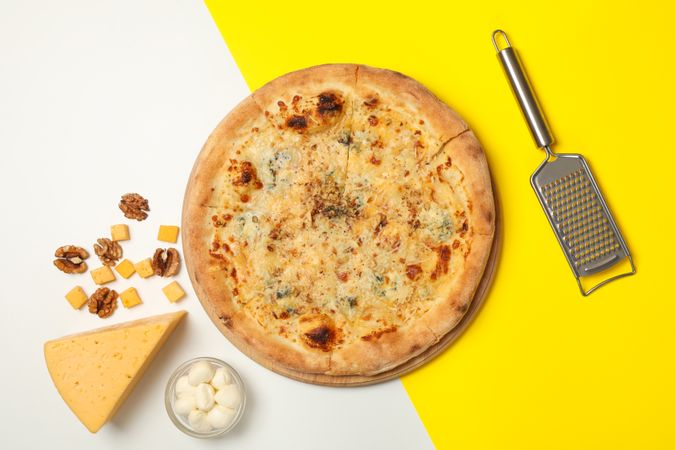 Cheese pizza and ingredients on two tone background