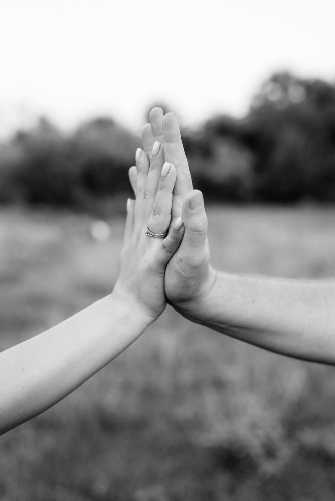 Grayscale photo of two hands of two people holding