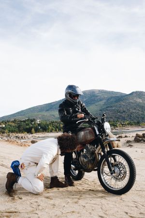 Mechanic checking motorcyclist bike in the mountains