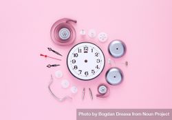 Clock components organized in a circle over pink background 56kBL4