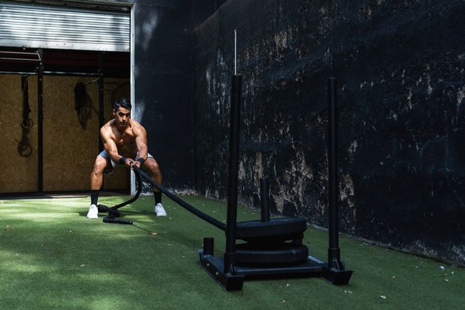 Muscular Hispanic sportsman pulling weight sled