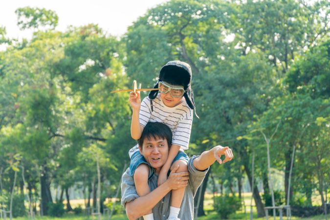 Father and son playing with toy plane in green public park