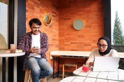 Two Young Asian Working People, Discussing at the Cafe Table, Working with Laptop Explaining File on Screen