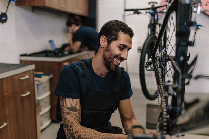 Smiling man working on a bicycle in a repair shop
