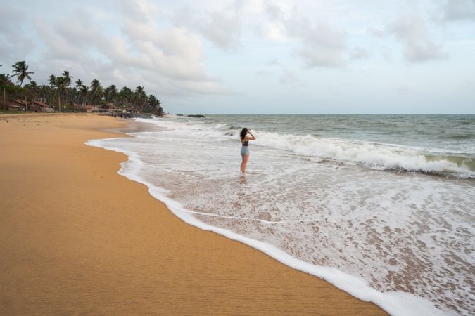 Woman in beachwear walking on sand barefoot