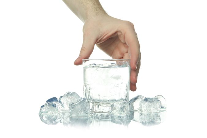 Hand lifting crystal rocks glass full of water
