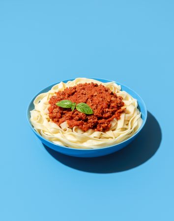 Bolognese pasta dish isolated on a blue background