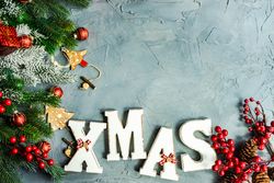 Wintry pine branch with "XMAS" letters on grey background