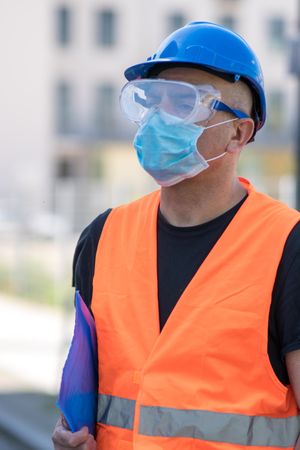 Man in orange safety jacket wearing blue goggles and helmet and facemask