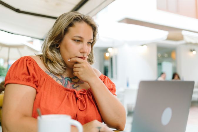 Thoughtful woman working on laptop in cafe