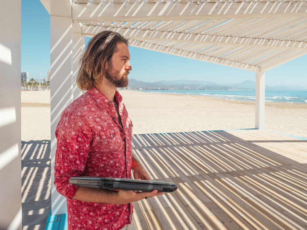 Man using laptop on beach
