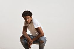 Man crouching down in studio shoot and looking at camera with serious expression
